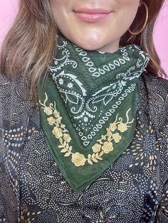 a woman wearing a green bandana with gold designs on it's neck and large hoop earrings