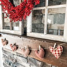 red and white heart shaped ornaments hanging on a mantle in front of an old window