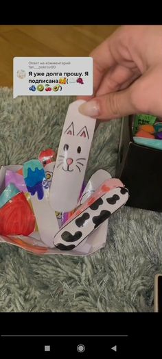 someone is holding up a card with a cat on it and some other items in the background