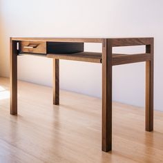 a wooden desk with a drawer underneath it on a hard wood flooring area next to a white wall