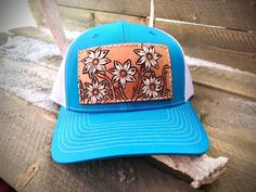 A bright baby blue  Trucker hat decked out with a field of wildflowers on a leather patch! These hats are super comfortable and have an adjustable snap back.  PLEASE READ: This item is for pre-ordering, and is made to order! Once purchased, this item will take approximately two weeks to re-create. Item will be a close replica, but each one will have slight variances in color, carving, etc. as I am not perfect, and leather is not perfect either! *All of HCL's leather products are cut, designed, dyed, painted, sewn, and assembled by hand. Items will not be machine perfect, but I try my hardest to get them there! Please keep in mind that leather may have natural scuffs, brand marks, discoloration, etc. It's all part of what makes leather so beautiful and unique! Blue Flat Bill Hats For Spring, Western Style Snapback Hat For Spring, Adjustable Blue Trucker Hat For Rodeo, Blue Adjustable Trucker Hat For Rodeo, Blue Snapback Hat For Rodeo, Blue Country Style Hat, Country Style Blue Hat, Spring Snapback Hats For Country Events, Snapback Hats For Country Events In Spring