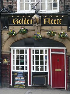 the entrance to golden fleece restaurant with red doors and flowers hanging from it's windows