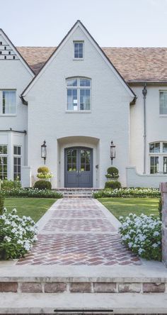 a white house with brick walkway leading up to the front door and entryway area