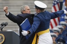 two men in uniforms are standing at a podium and one is holding his arms up