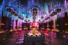 a large room filled with lots of tables and chairs covered in purple, green, and blue lights