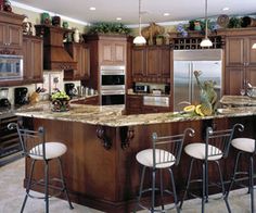 a large kitchen with an island in the middle and three bar stools at the end