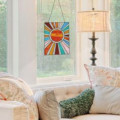 a living room filled with furniture and a large window covered in stained glass sunburst