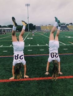 two girls doing handstands on a football field