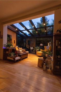 a living room filled with lots of furniture under a glass ceiling over a wooden floor