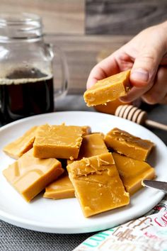 a person is holding a piece of peanut butter on a plate next to a jar of honey