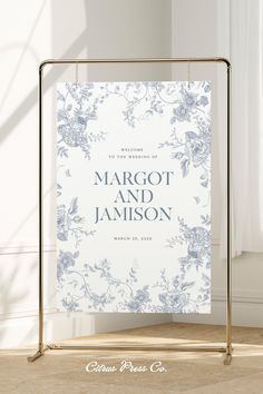 a white and blue wedding card with flowers on it, in front of a window