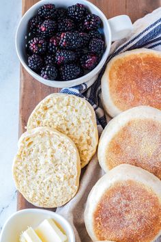 bread, butter, and berries are on a cutting board next to some crackers