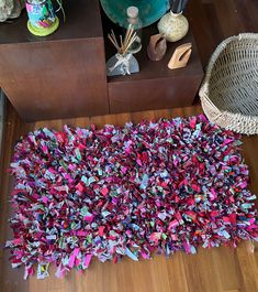 a pile of colorful paper on top of a wooden floor next to a wicker basket