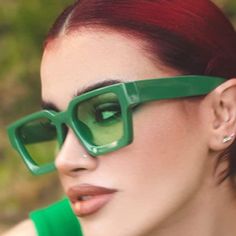 a woman with red hair wearing green glasses