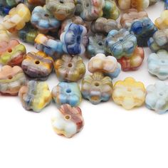 many different colored glass beads on a white surface with one bead in the middle