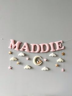 a baby's name sign hanging on the wall with clouds and stars around it