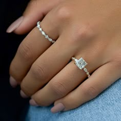 a woman's hand with two diamond rings on her left and the other hand holding an engagement ring