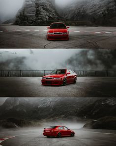 the red car is driving down the road with mountains in the background and foggy skies