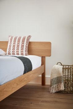 a bed with pillows and blankets on top of it next to a wicker basket