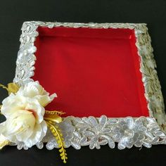 a white flower sitting on top of a red and silver tray with flowers in it