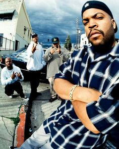 a group of men standing next to each other on a street with buildings in the background