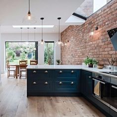 an open kitchen with blue cabinets and wood flooring in the center, along with brick walls