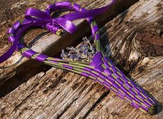 a bouquet of flowers is tied to a piece of wood with purple ribbons on it