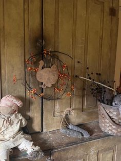 a small doll sitting on top of a wooden bench next to a basket and turkey ornament