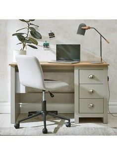 an office desk with a laptop computer on top of it and a potted plant in the corner