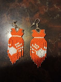 two orange and white beaded earrings on a table