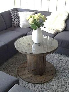 a living room with grey couches and white flowers in a vase on the coffee table