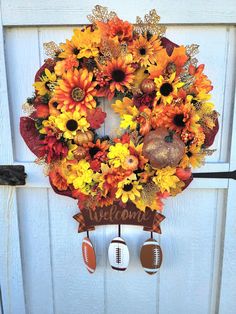 a wreath with footballs and sunflowers is hanging on the front door to welcome fall