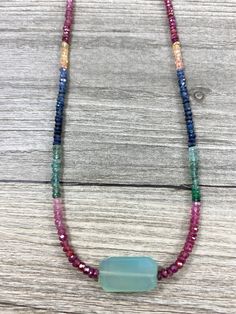 "A beautiful sky blue faceted slab shaped chalcedony is centered on a glimmering strand of multicolored sapphire rondelles.  Sapphires set off a gorgeous rainbow of colors, including red, pink, yellow, green and blue.  Finished with a gold filled lobster clasp. A unique piece of jewelry from La Vie en Rose Jewelry Collection.  Necklace measures 16 3/4\" L and chalcedony slab is approx. 1\"  All jewelry comes in a natural cotton muslin drawstring bag.  Perfect for gift giving! Add more beauty to your life!" Multicolor Agate Crystal Necklace With Faceted Beads, Multicolor Agate Jewelry With Faceted Beads, Turquoise Agate Faceted Bead Necklaces, Artisan Gemstone Rondelle Necklace, Turquoise Agate Faceted Beads Necklace, Turquoise Agate Necklace With Faceted Beads, Blue Chalcedony Gemstone Bead Necklaces, Blue Rondelle Natural Gemstones, Bohemian Faceted Rondelle Necklace