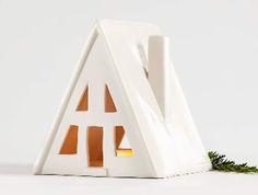 a white house shaped like a triangle with trees growing out of the front and side