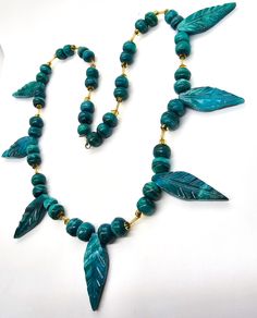 Malachite Chrysocolla beaded leaf 8mm hand crafted artisan vintage necklace. Good used condition with little to no signs of normal wear. Stunning beads show beautiful banding with a mixed matrix of blue Chrysocolla and green malachite. These beads are tightly strung with a crafted hook clasp. Each section of beads has 4 roughly 8mm beads with a carved leaf between yellow seed/accent beads. Each bead is uniquely carved and polished so you can see and feal the different natural textures. Necklace measures 23 inches long. Turquoise Malachite Necklaces With Round Beads, Handmade Turquoise Malachite Necklaces, Handmade Turquoise Malachite Necklace, Artisan Handmade Chrysocolla Beaded Necklaces, Handmade Malachite Bohemian Necklace, Handmade Bohemian Malachite Necklace, Handmade Malachite Round Bead Necklace, Handmade Green Chrysocolla Necklace, Handmade Turquoise Beaded Necklaces Nature-inspired