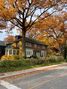 a red brick house surrounded by trees with yellow leaves