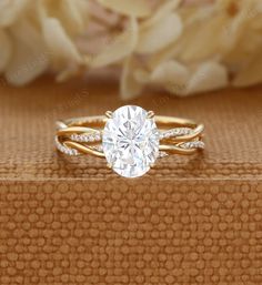 an oval cut diamond engagement ring on top of a book with flowers in the background