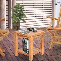 two wooden chairs and a small table on a deck with a plant in the corner