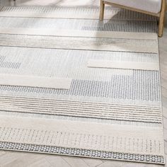 an area rug is shown with white and blue patterns on the floor, along with a beige chair