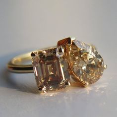 two engagement rings with an orange and white diamond in them, on a light background