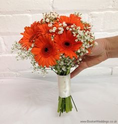 a bouquet of orange and white flowers in someone's hand