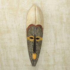 an african mask hanging on the wall in front of a white background with yellow accents