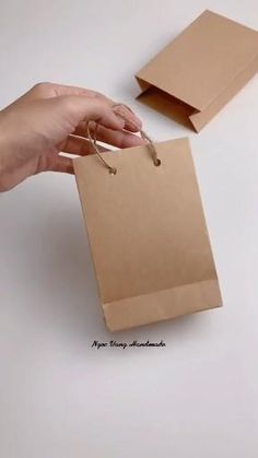 a hand holding a brown paper bag with string attached to it and another person's hand reaching out