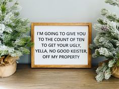 two potted plants sitting on top of a wooden table next to a framed sign