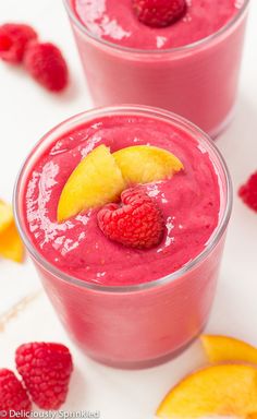 two glasses filled with raspberry smoothie and garnished with a slice of fruit