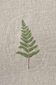 a small green leaf is embroidered on the side of a linen material fabric, which has been stitched together