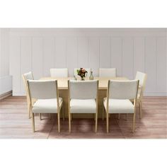 a dining room table with six chairs and a vase on the center piece, in front of a white paneled wall