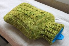 a green knitted cup cozy sitting on top of a pillow