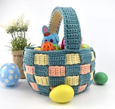 a crocheted basket filled with lots of toys and eggs next to a potted plant