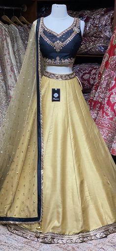 Bright gold plain skirt with black foiled work waist border paired with contrasting black kundan, stone and zardozi embroidery blouse and butti net dupatta. Fabric: Raw Silk This outfit can be customized in multiple colors and specific to client measurements. 90 days of production time is required and are for bulk orders only! Orders are processed in store only! Final fittings/alterations not included. Minimum Order Quantity- 4 pieces Designer Gold Raw Silk Lehenga, Gold Raw Silk Lehenga With Dupatta, Gold Anarkali Choli In Raw Silk, Gold Lehenga With Dupatta In Raw Silk, Gold Raw Silk Lehenga With Zari Work, Designer Gold Art Silk Lehenga, Designer Gold Art Silk Choli, Designer Gold Choli In Art Silk, Gold Anarkali Choli In Art Silk